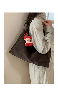 Detail of dark brown leather tote bag with a unique red apple core plush pendant charm