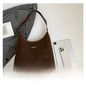 Deep brown matte leather tote bag with gold logo lettering in a minimalist office setting