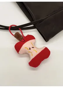 Close-up of a creative apple core plush charm with smiling face hanging on a bag