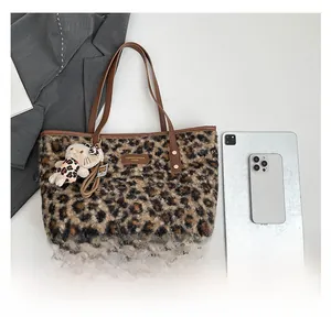 Detail view of leopard print plush tote bag with brown leather handles and brand name plate