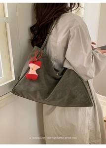 Deep olive green suede tote bag styled with a red apple plush charm for a retro vibe