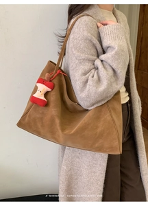 Brown suede tote bag styled with a minimalist retro vibe and an apple core pendant charm