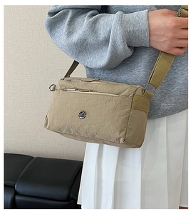 Lifestyle shot of khaki nylon crossbody bag with pleated texture and adjustable strap