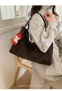 Deep brown oversized suede tote bag with a red apple charm shown on a shoulder