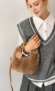 Detailed shot of brown faux fur bucket bag with gold hardware and leather strap