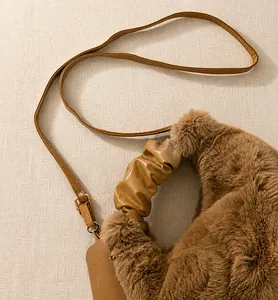Detail view of brown plush tote bag with khaki pleated faux leather handle