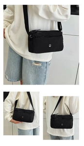 Close-up of lightweight black nylon crossbody bag featuring multi-pocket zipper design