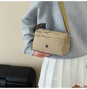 Close-up of khaki nylon crossbody bag with multi-layer zippers and metallic M logo