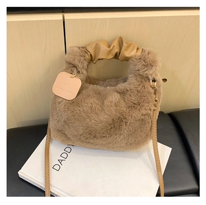 Detail der Plüschhandtasche mit gerafftem PU-Griff und schickem Textanhänger