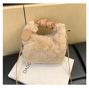Detail der beigen Plüschtasche mit braunem Ledergriff in Faltenoptik und schmalem Schultergurt