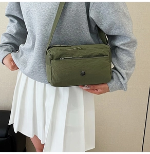 Detail view of military green nylon crossbody bag with adjustable strap and metal logo