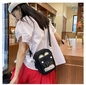 Detalle del bolso ita de lona negra con ventana transparente de orejas de gato y pines