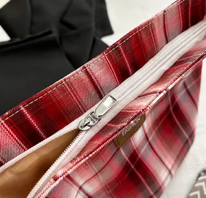 Gros plan sur la fermeture éclair en métal et le tissu à carreaux rouge du sac cabas