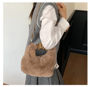 Braune Plüschhandtasche mit Lederriemen und Faltenwurf-Griff am Model getragen