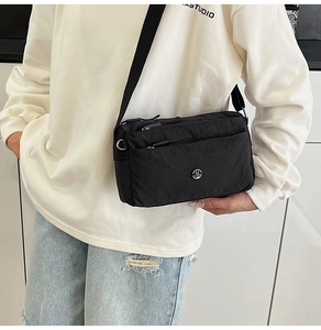 Detailed shot of multi-layer nylon crossbody bag with silver M logo and wide strap