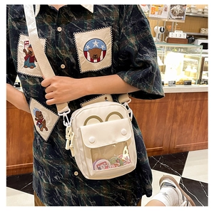 Detalle del bolso bandolera de lona crema con ventana transparente en una acogedora cafetería