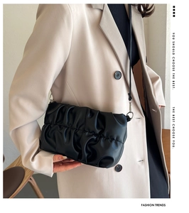 Detail of black pleated cloud bag with soft leather texture and silver metal rings