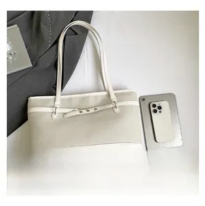 Top-down view of oatmeal knit tote bag with white leather trim and metal eyelet details