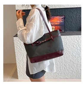 Detail of large woven tote bag in dark gray and burgundy trim worn by model