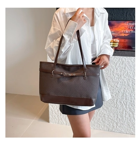 Detail of dark brown tote bag featuring textured weave and leather shoulder strap