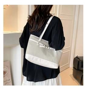 Detailed back view of model wearing a two-tone woven tote bag with white leather straps