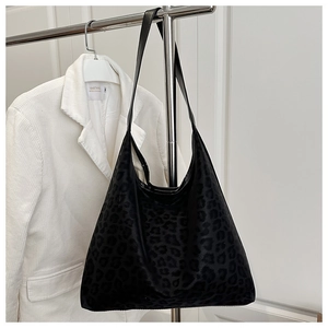 Detalle de un bolso grande con estampado de leopardo colgado en una percha con chaqueta