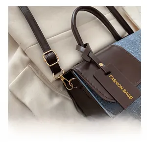 Detail of crossbody bag with brown leather and blue denim patchwork with golden hardware