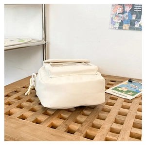 Detalle del bolso bandolera de lona crema con ventana de PVC transparente y nudo lateral