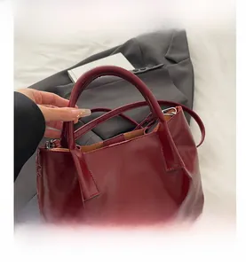 Detailed view of glossy burgundy leather tote bag with round handles and fine stitching