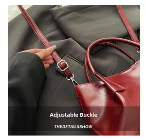 Detail view of burgundy leather tote shoulder strap with adjustable silver metal buckle