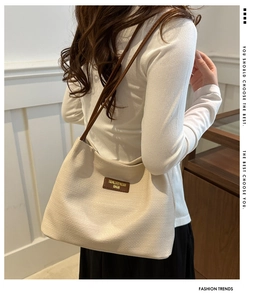 Détail du cabas tissé beige avec fines bretelles en cuir marron porté à l'épaule par un modèle