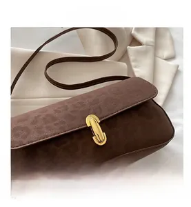 Detail of dark brown faux suede shoulder bag with a gold rectangular metal turn-lock