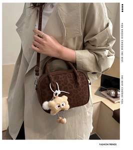 Detail of leopard print handbag with soft texture and a yellow plush bear pendant