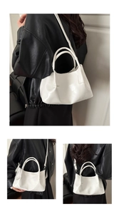 Close-up of white glossy tote bag with pleated texture and adjustable shoulder straps