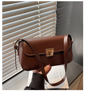 Détail d'un sac à bandoulière en cuir marron foncé avec boucle dorée et texture lisse