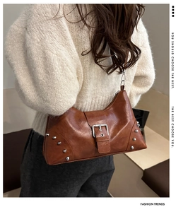 Detail of vintage caramel leather shoulder bag with silver studs and buckle strap on model