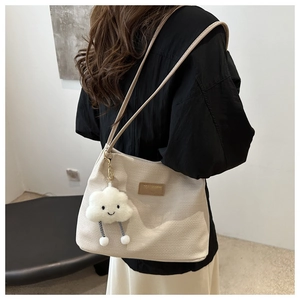 Détail du sac cabas gaufré avec bandoulière en cuir beige et breloque nuage