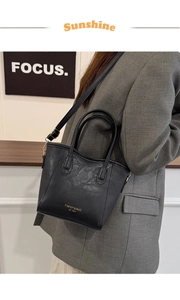 Detail of black faux leather tote with golden lettering and adjustable shoulder strap