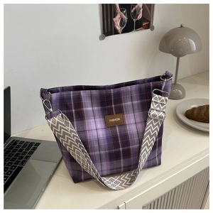 Détail du sac cabas à carreaux violets avec écusson en cuir et bandoulière tissée
