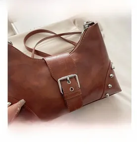 Close-up of vintage brown oil-wax leather bag with silver studs and buckle detail