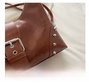 Close-up of brown vintage shoulder bag featuring silver rivets and metal buckle detail