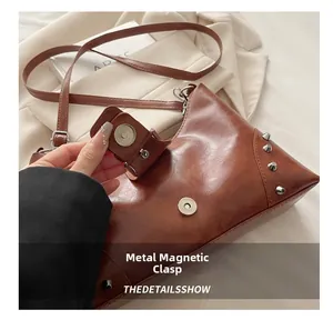 Close-up of silver magnetic clasp and rivet hardware on brown leather tote bag