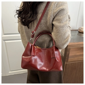 Burgundy pleated faux leather handbag shown on shoulder with elegant commuter style