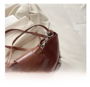 Close-up of smooth silver zipper and rivet details on the brown leather hobo bag