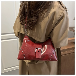 Dettaglio borsa hobo in pelle rossa con rivetti argento e fibbia sulla spalla