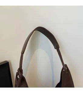 Détail de la bandoulière en cuir marron foncé avec nœud et boucles métalliques