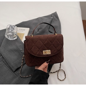 Detailed view of brown quilted velvet bucket bag featuring a gold clasp and chain strap