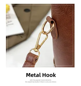 Detailed close-up of premium gold swivel metal hook on brown lychee texture leather bag