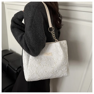 Détail du sac cabas plissé blanc avec bandoulière en chaîne dorée et plaque de logo