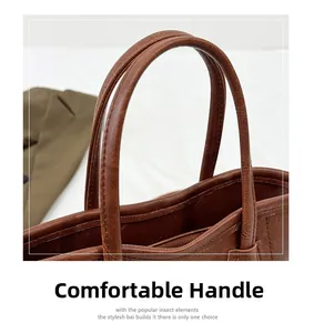 Detail of comfortable brown leather handle with reinforced stitching on a bucket bag